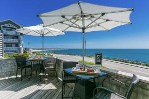 a patio with tables and umbrellas and the ocean at Inn on the Sound in Falmouth