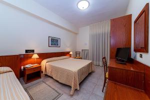 a hotel room with two beds and a television at Il Nocchiero City Hotel in Soverato Marina