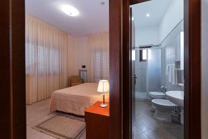 a bedroom with a bed and a bathroom with a sink at Il Nocchiero City Hotel in Soverato Marina