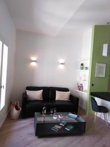 a living room with a black couch and a table at APPART AIX MAZARIN in Aix-en-Provence