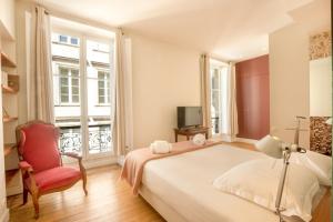 1 dormitorio con 1 cama, 1 silla y TV en Appartement Luxe avec Climatisation Parking Vue Exeptionnelle en Burdeos