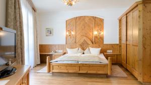 a bedroom with a bed with a wooden headboard at Hotel Garni Castel B&B in Ischgl