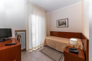 a bedroom with a bed and a desk with a television at Il Nocchiero City Hotel in Soverato Marina