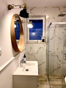 a bathroom with a sink and a mirror and a window at Sosnowe Zacisze Apartament in Łukęcin