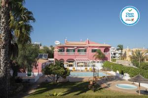 a pink house with a swimming pool in front of it at Solar de Mos in Lagos