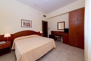 a bedroom with a bed and a desk with a computer at Il Nocchiero City Hotel in Soverato Marina