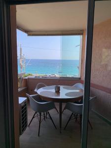 uma mesa e cadeiras num quarto com vista para o oceano em Magnifique appartement pied dans l'eau em Cannes