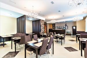 a restaurant with tables and chairs and chandeliers at Gokai Hotel in Astana