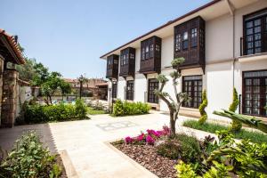 a courtyard of a building with a tree and flowers at Livia Garden Hotel in Selçuk