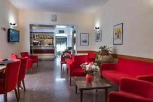 a waiting room with red chairs and a bar at Il Nocchiero City Hotel in Soverato Marina