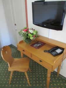 einen Holzschreibtisch mit einem TV und Blumen darauf in der Unterkunft Hotel & Restaurant Schimmelreiter in Silberstedt