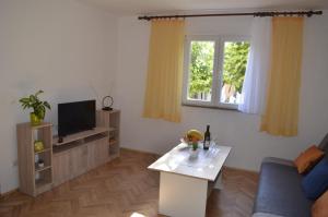 ein Wohnzimmer mit einem Sofa und einem TV in der Unterkunft Apartment Ana in Kaštel Sućurac