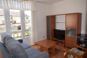Una sala de estar con un sofá y un televisor. en Apartamentos VIDA Corcubión, en Corcubión
