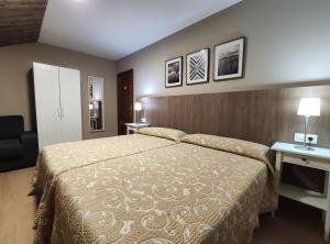 1 dormitorio con cama y pared con cuadros en Hostal-Restaurante Paris, en Forcarei
