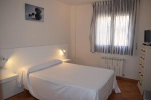 Un dormitorio blanco con una cama blanca y una ventana en Apartamentos VIDA Corcubión, en Corcubión