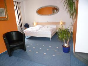 ミンデンにあるHotel Restaurant Marbellaのベッドルーム1室(ベッド1台、椅子、植物付)