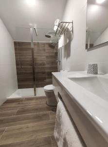 Un baño blanco con inodoro y lavabo. en Hostal-Restaurante Paris, en Forcarei