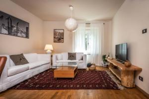 a living room with a white couch and a tv at Villetta Vallesinella in Madonna di Campiglio