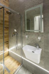 ein Badezimmer mit einem weißen Waschbecken und einer Dusche in der Unterkunft Doroshenko street for 4 guests in Lwiw