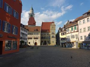 una calle de la ciudad con edificios y una torre del reloj en "Klein & Fein", en Überlingen