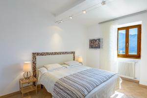 a white bedroom with a bed and a window at Casa Artis in Gravedona