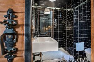 a bathroom with a sink and black tiled walls at Lemon Tree Stay in Faro