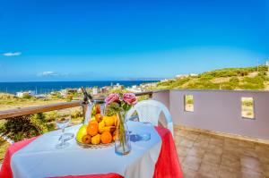 a table with fruit and flowers on a balcony with the ocean at Gregory Village Sea View in Stalos