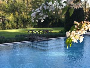 uma ponte de madeira sobre uma piscina com flores brancas em Le Moulin du Roc em Brantôme