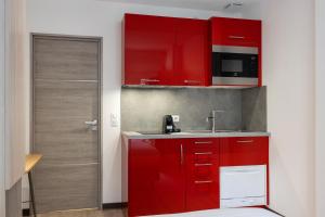 a red kitchen with a sink and a microwave at Appartements French Riviera Confidential Centre Ville Juan les Pins proche des plages in Juan-les-Pins