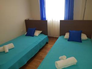 2 łóżka w pokoju z niebieską pościelą i niebieskimi poduszkami w obiekcie Koukaki Apt 5 min walk to Acropolis w Atenach