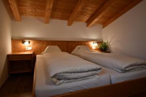 a bedroom with two beds with white sheets at Haus Kargruber in Santa Maddalena