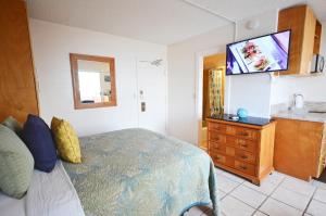Schlafzimmer mit einem Bett und einem Flachbild-TV in der Unterkunft Sea Shore 75 Steps from Waikiki Beach and Sleeps 1 - 3! in Honolulu