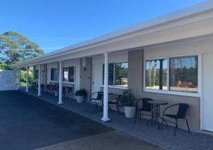 a building with chairs and tables and windows at Ulladulla Motel in Ulladulla