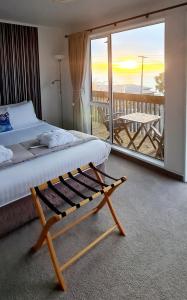 a bedroom with a bed and a balcony with a table at Kaka Point Spa Accommodation - Catlins in Kaka Point