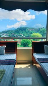 two beds in a room with a large window at Hoang Kim Ha Giang Hotel in Ha Giang