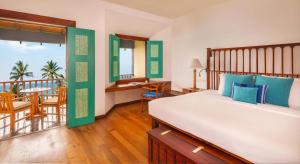 a bedroom with a bed and a balcony with a table at Jetwing Lighthouse in Galle