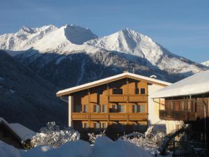 a building with snow covered mountains in the background at Gästehaus Zedlacherhof in Matrei in Osttirol