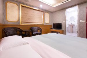 Best Hotel في تايبيه: غرفة نوم بسرير ابيض وتلفزيون