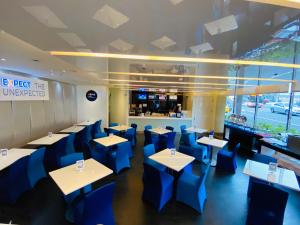un restaurante con mesas y sillas azules y una barra en Holiday Inn Express Taoyuan, an IHG Hotel en Taoyuan