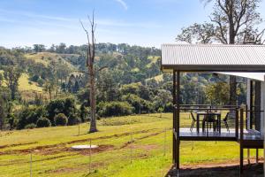 una casa con una terraza con una mesa en un campo en Valley Cabins By The Creek en Imbil