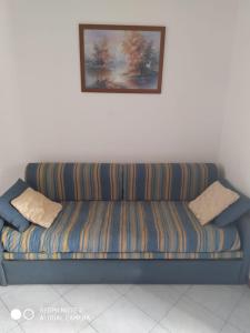 un sofá azul sentado bajo una pintura en la pared en Casa Totano, en Canneto