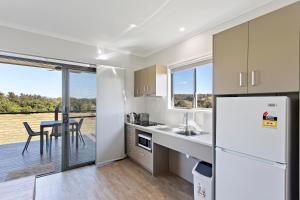 a kitchen with a refrigerator and a table with a view at Valley Cabins By The Creek in Imbil