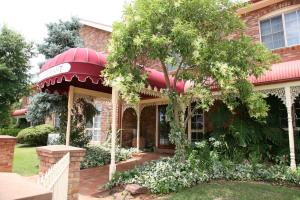 a house with a red awning and a tree at Australian Heritage Motor Inn in Dubbo