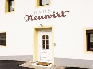 - un bâtiment blanc avec une porte blanche et un panneau dans l'établissement Haus Neuwirt, à Sautens
