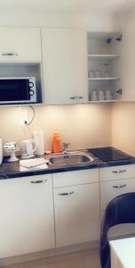 a white kitchen with a sink and a microwave at Apartment Lala in Interlaken