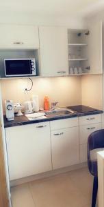 a white kitchen with a sink and a microwave at Apartment Lala in Interlaken