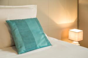 a blue pillow sitting on top of a bed at The Originals Boutique Hôtel Spa Beuzeville Honfleur Sud in Beuzeville