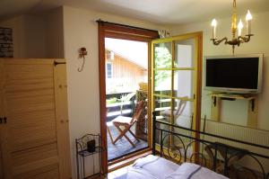 a room with a balcony with a television and a sliding glass door at Bed and Breakfast Lucia in Pfronten