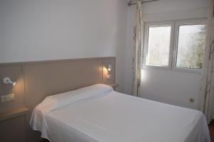 1 cama blanca en un dormitorio con ventana en Apartamentos VIDA Finisterre, en Finisterre