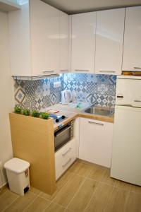 kuchnia z białymi szafkami, zlewem i lodówką w obiekcie Alkyon Perea Apartments w mieście Perea